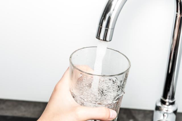 Et glas fyldes med vand fra hanen