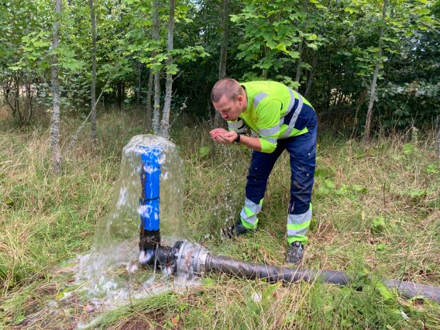 En medarbejder smager på drikkevand, som pumpes op af undergrunden i Anebjerg skov